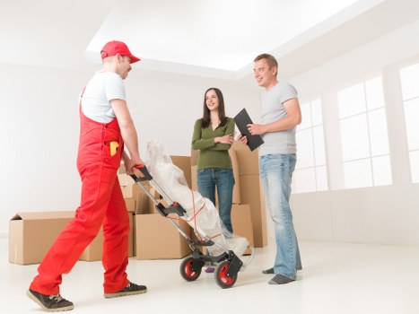 Professional removals crew loading items safely with PPE and straps